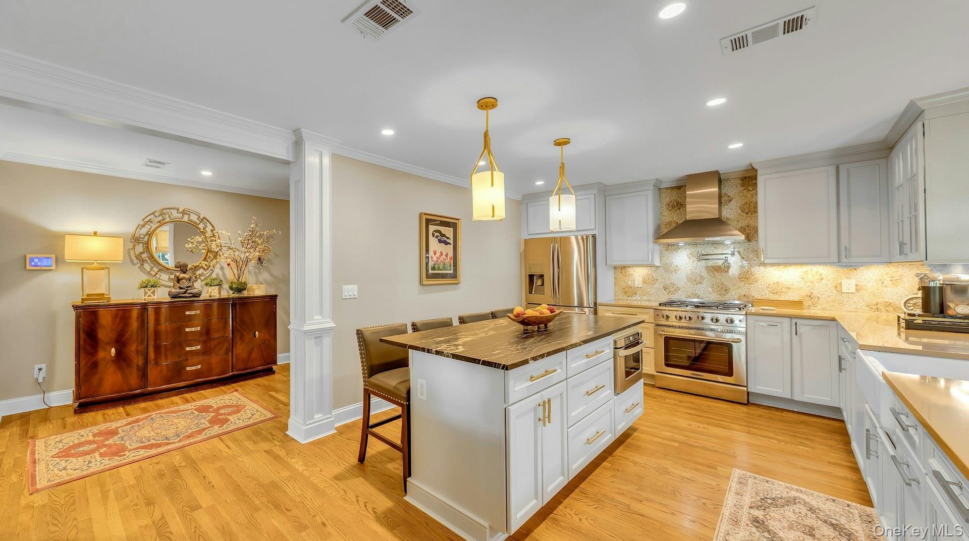 Hardwood flooring, white shaker cabinetry, stainless steel appliances, stone countertops, and recessed lighting