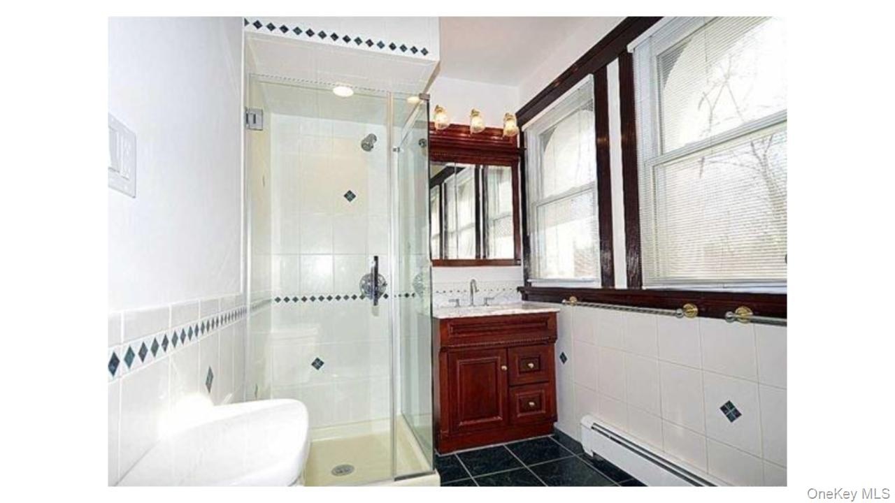 Glass-enclosed shower with white tiled walls