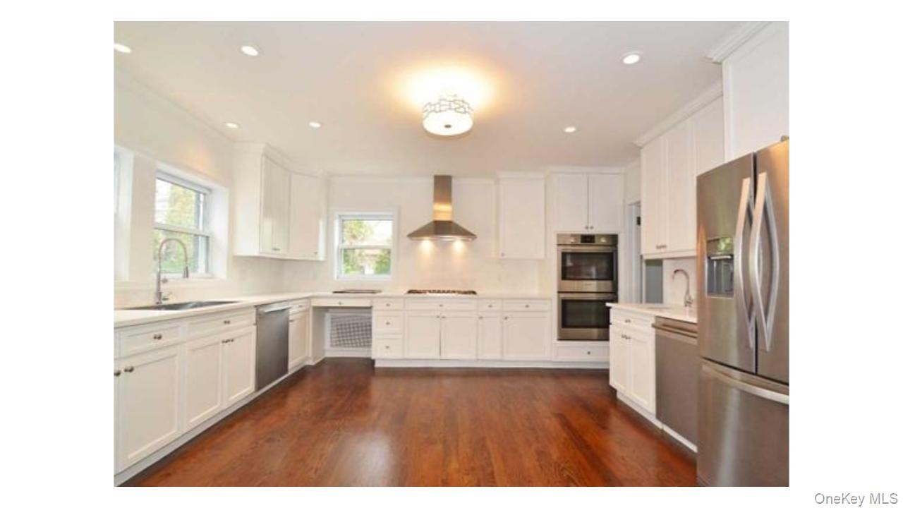 White cabinetry with stainless steel appliances, recessed lighting, wood-finish flooring, and a built-in double oven