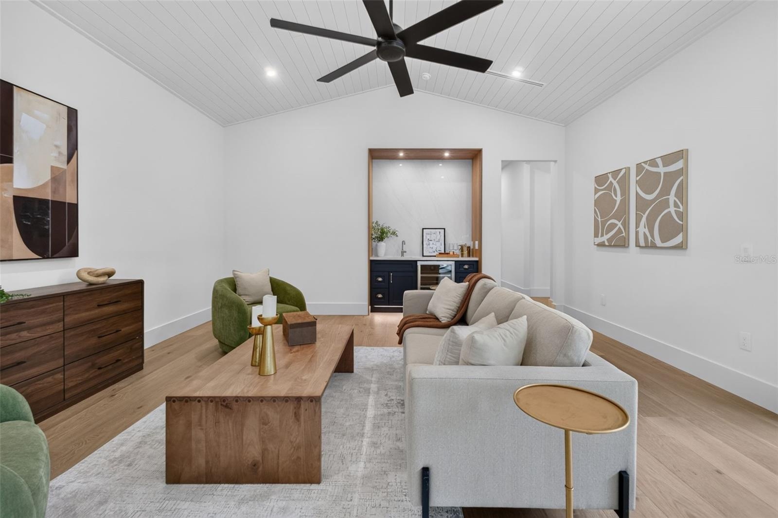 Game room features a wet bar with beverage refrigerator and two large sliding glass doors that provide direct access to pool and covered lanai