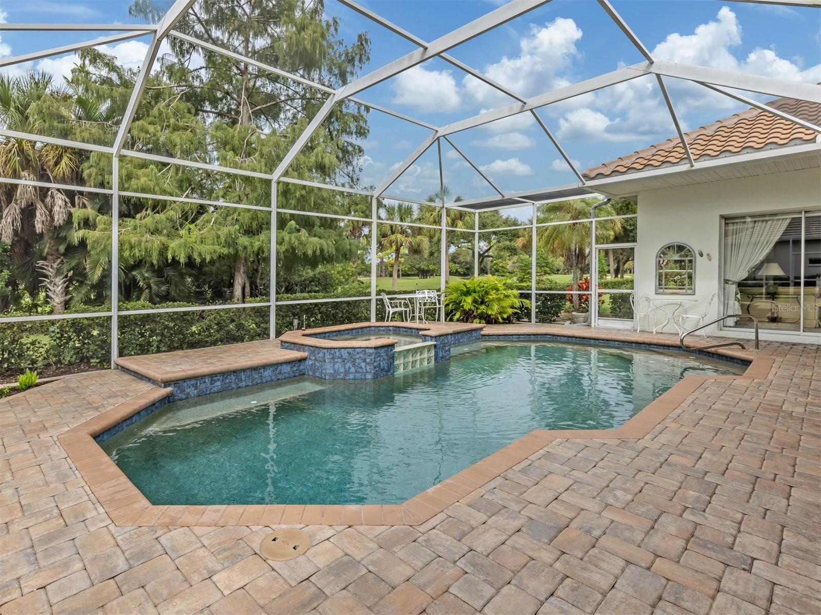 Screened lanai surrounded by lush gardens, offering privacy from the fairway.