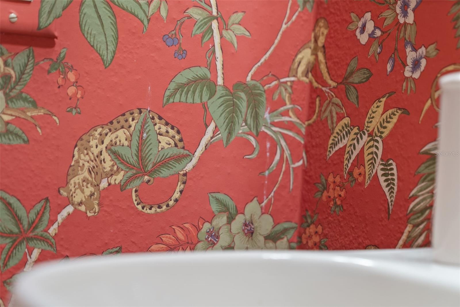 Cheerful patterned wallpaper and a classic pedestal sink bring personality to this bathroom.