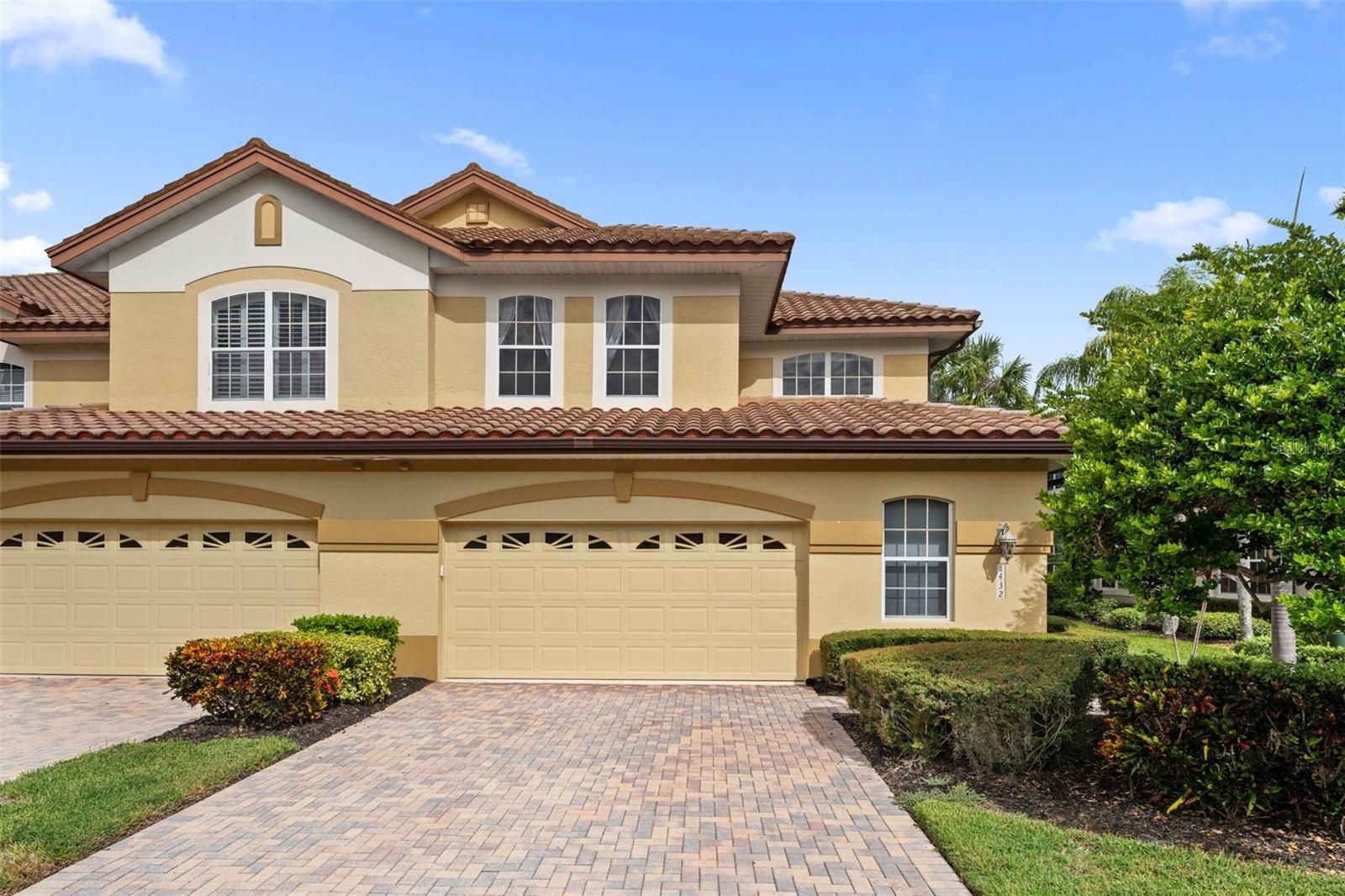 A paver driveway, tropical landscaping, and tile roof give this end-unit home inviting curb appeal.