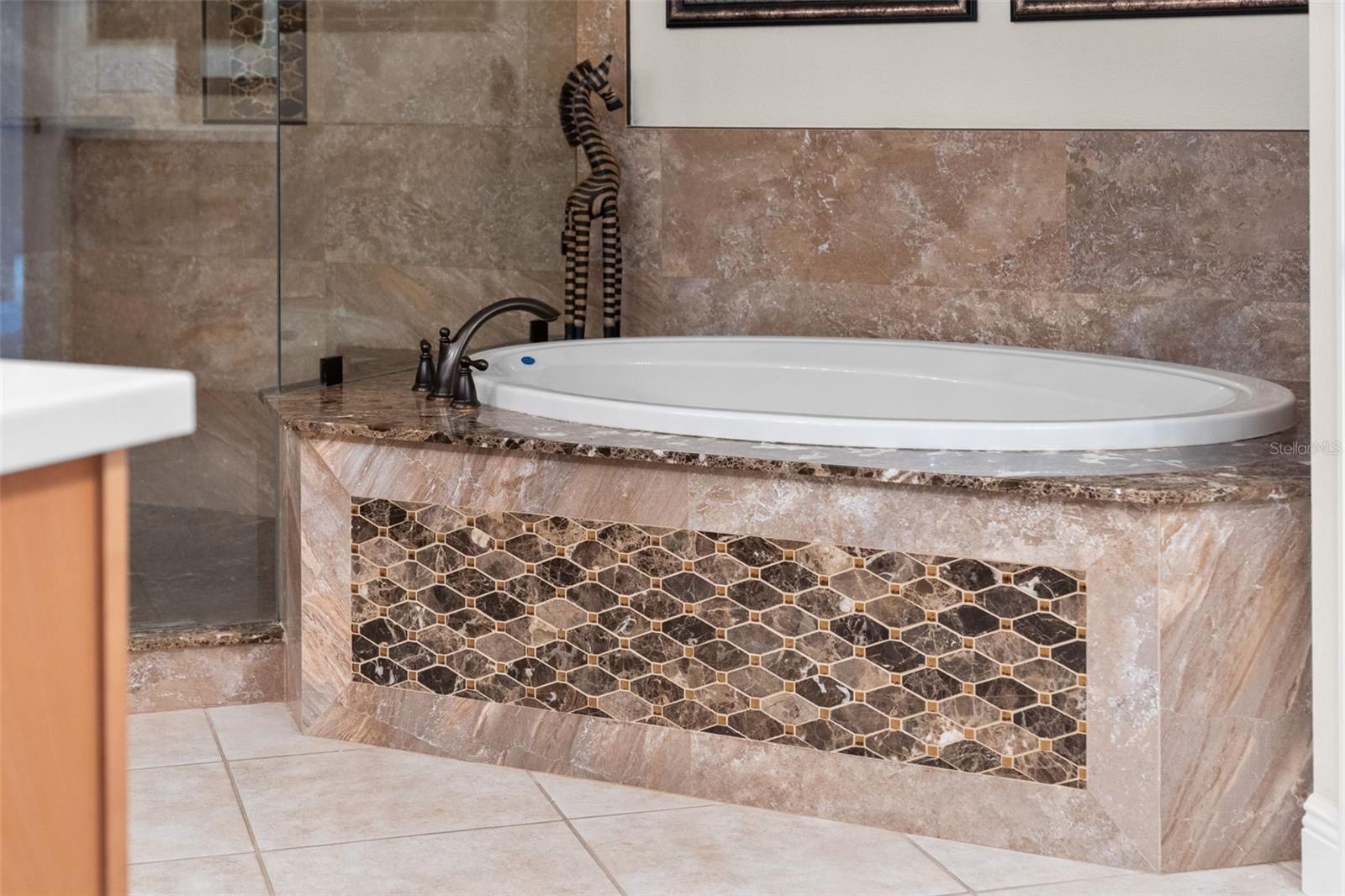 Unwind in the soaking tub, surrounded by rich stone finishes and decorative accents.