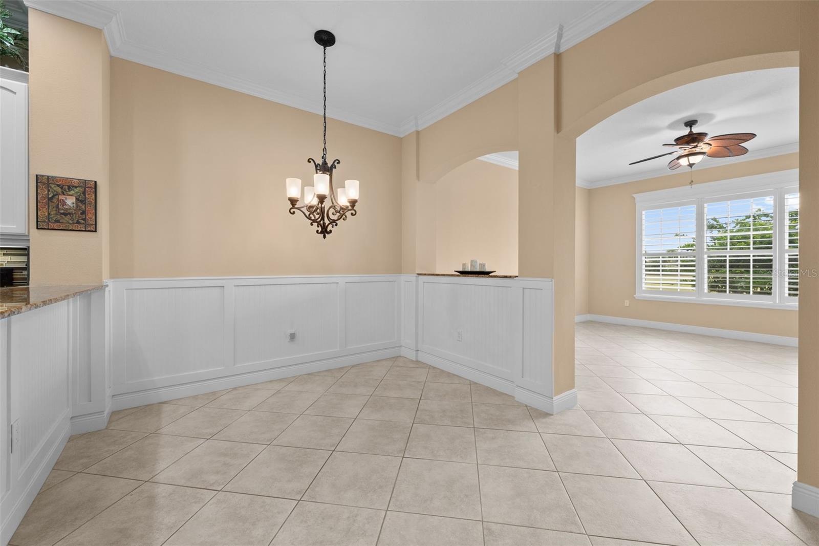 A charming spot for casual meals, framed by classic wainscoting and arched openings.
