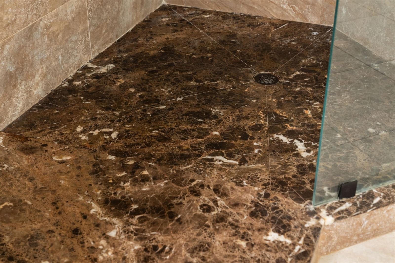 Richly patterned stone gives the walk-in shower a distinctive finishing touch.