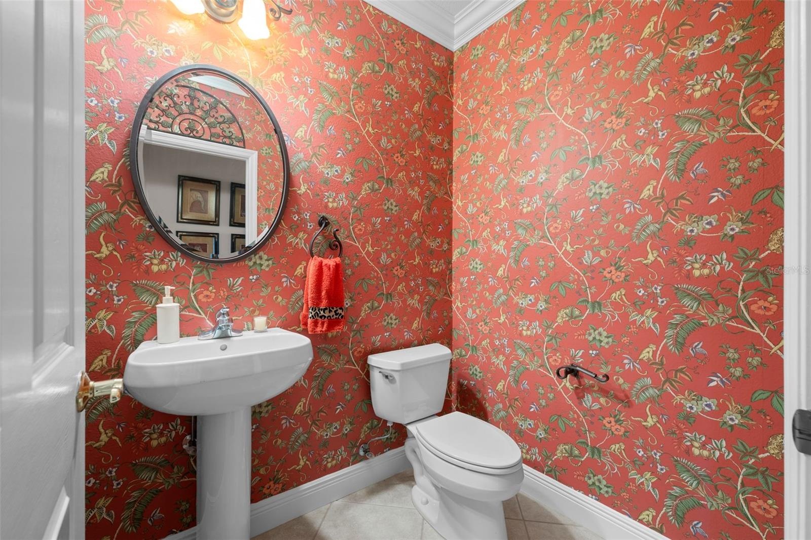 Cheerful patterned wallpaper and a classic pedestal sink bring personality to this bathroom.