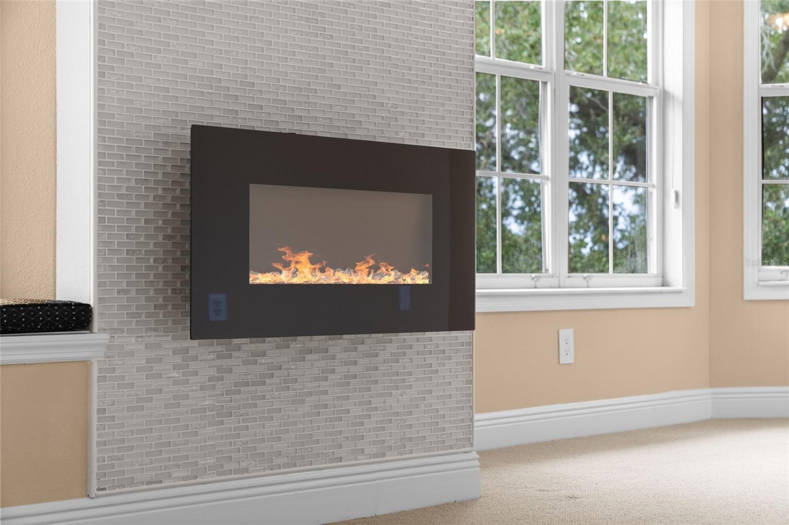 A fireplace with a mosaic tile surround adds a cozy touch to the primary suite.