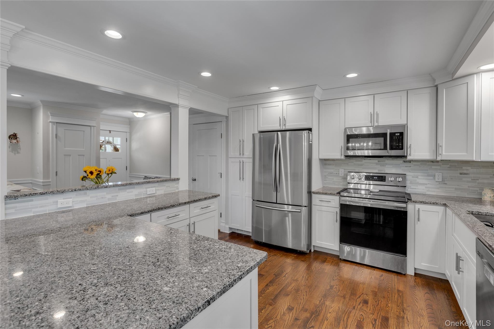 Granite countertops, white shaker cabinetry, stainless steel appliances, wood-finish flooring, and recessed lighting
