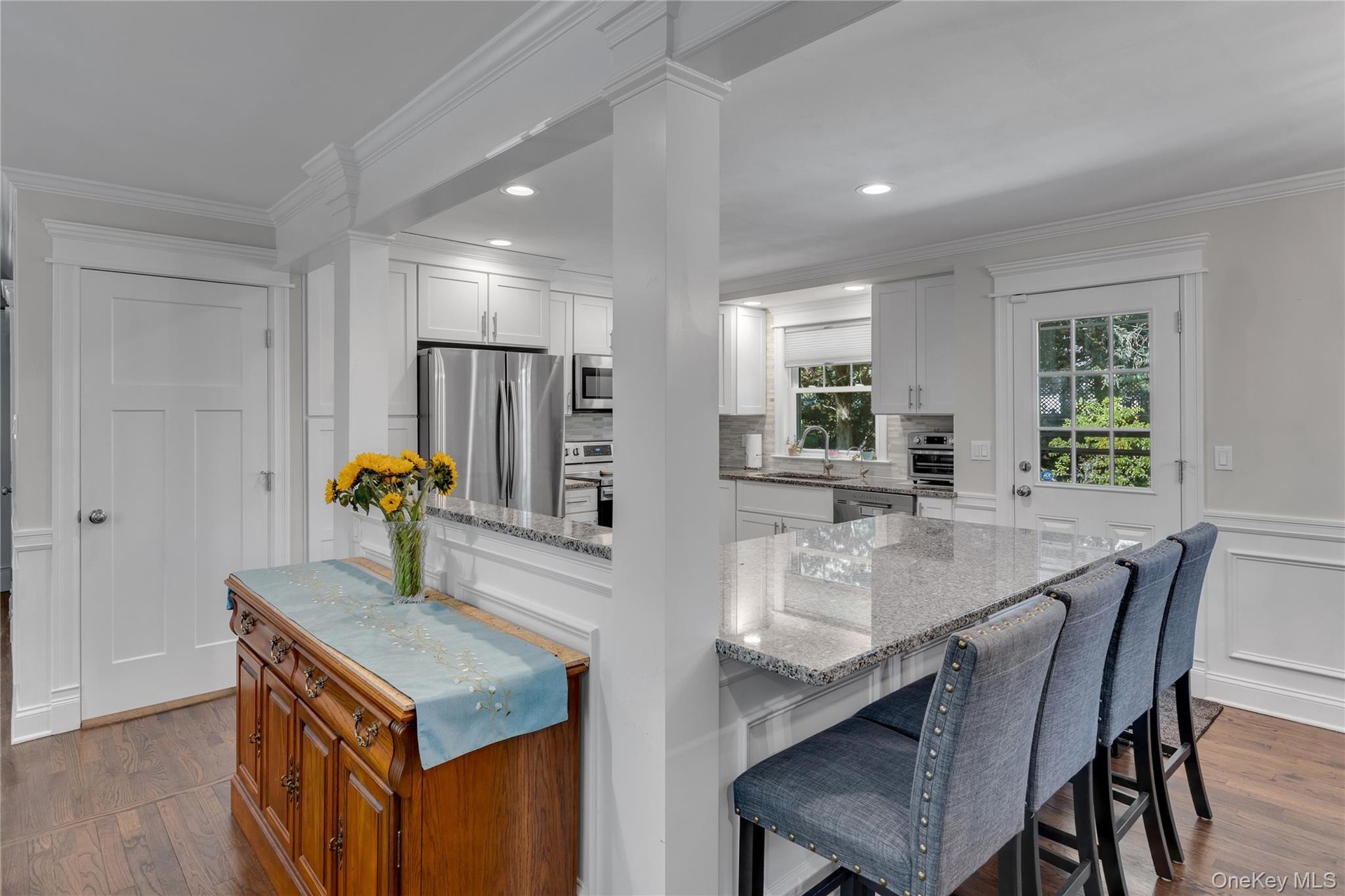 Bright, open-concept kitchen and dining area featuring white cabinetry, stainless steel appliances, quartz countertops, and a large center island with