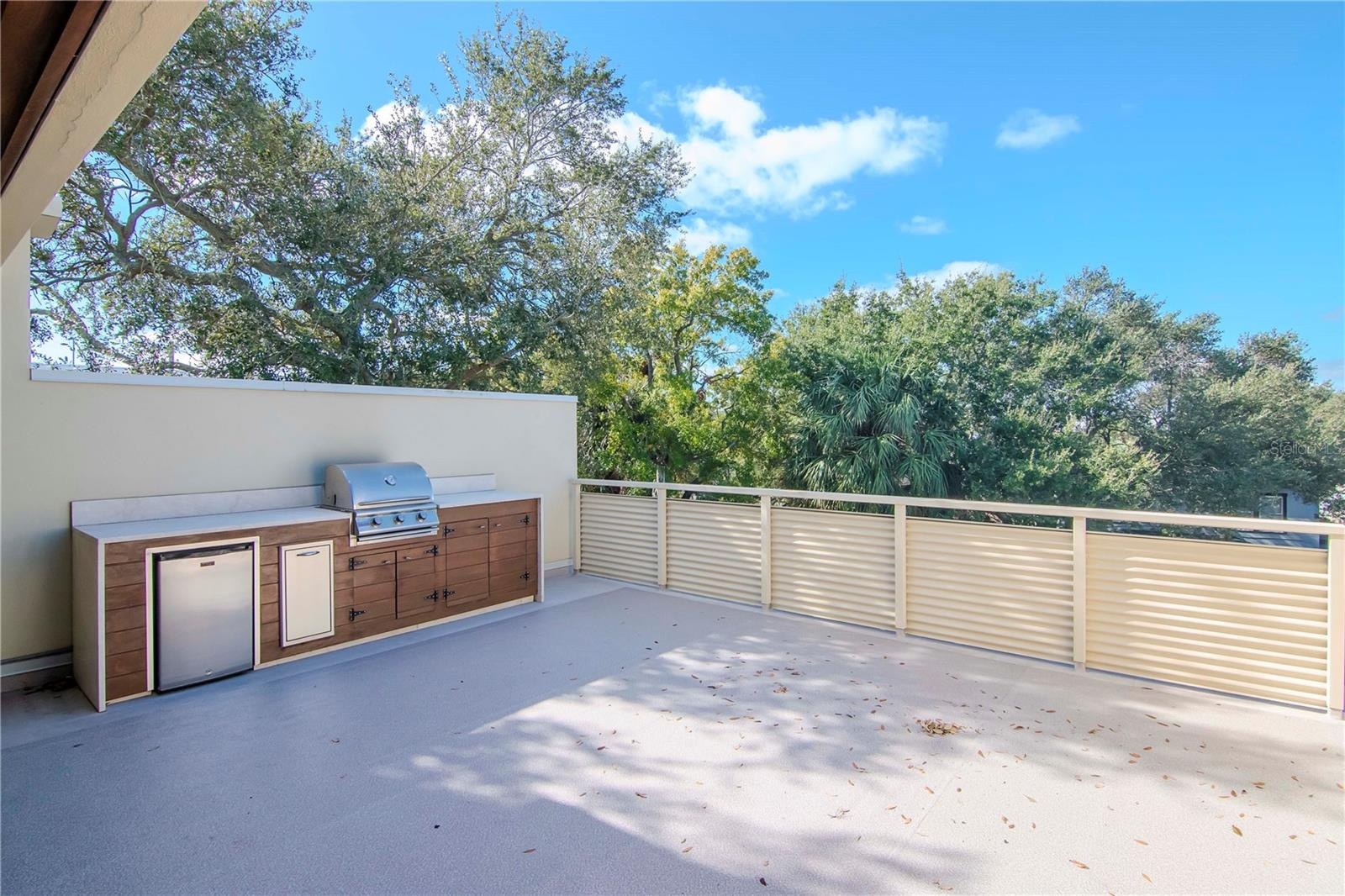 featuring an outdoor kitchen with grill and fridge