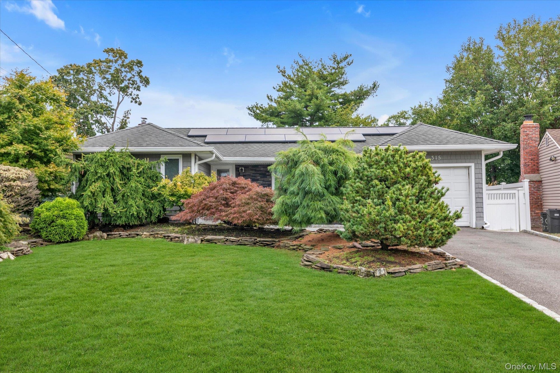 Ranch-style residence featuring a gray shingle facade, asphalt shingle roof, and solar panels