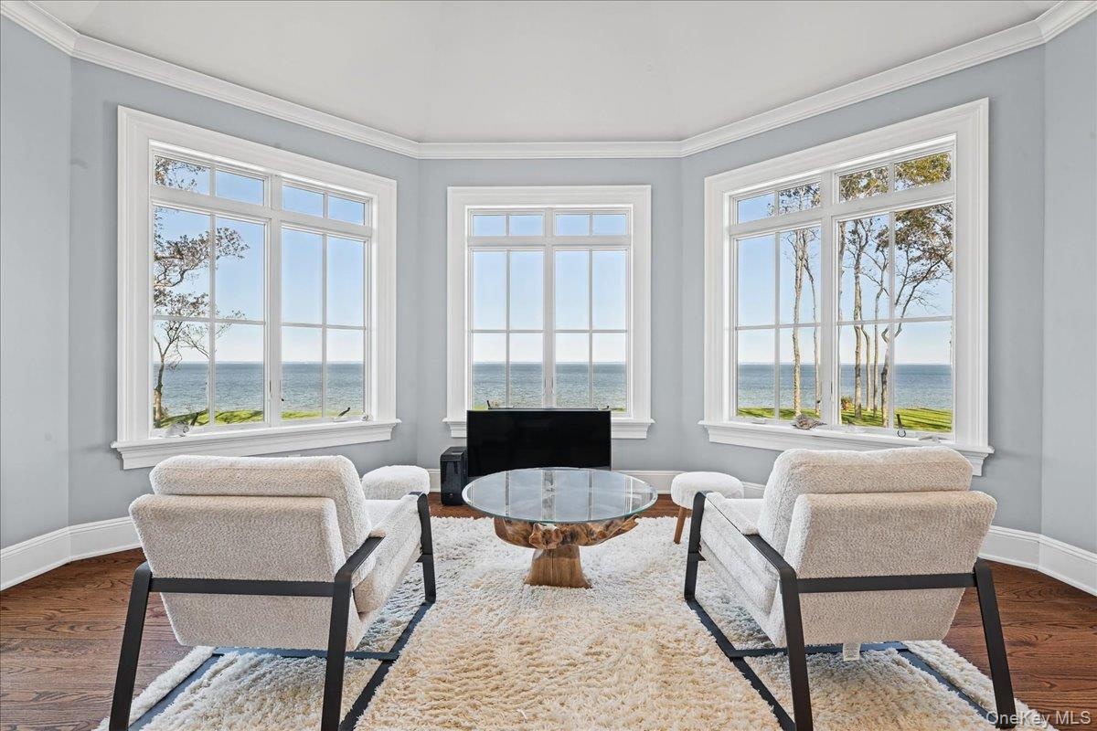 Bay window with water scenery, crown molding, and hardwood flooring