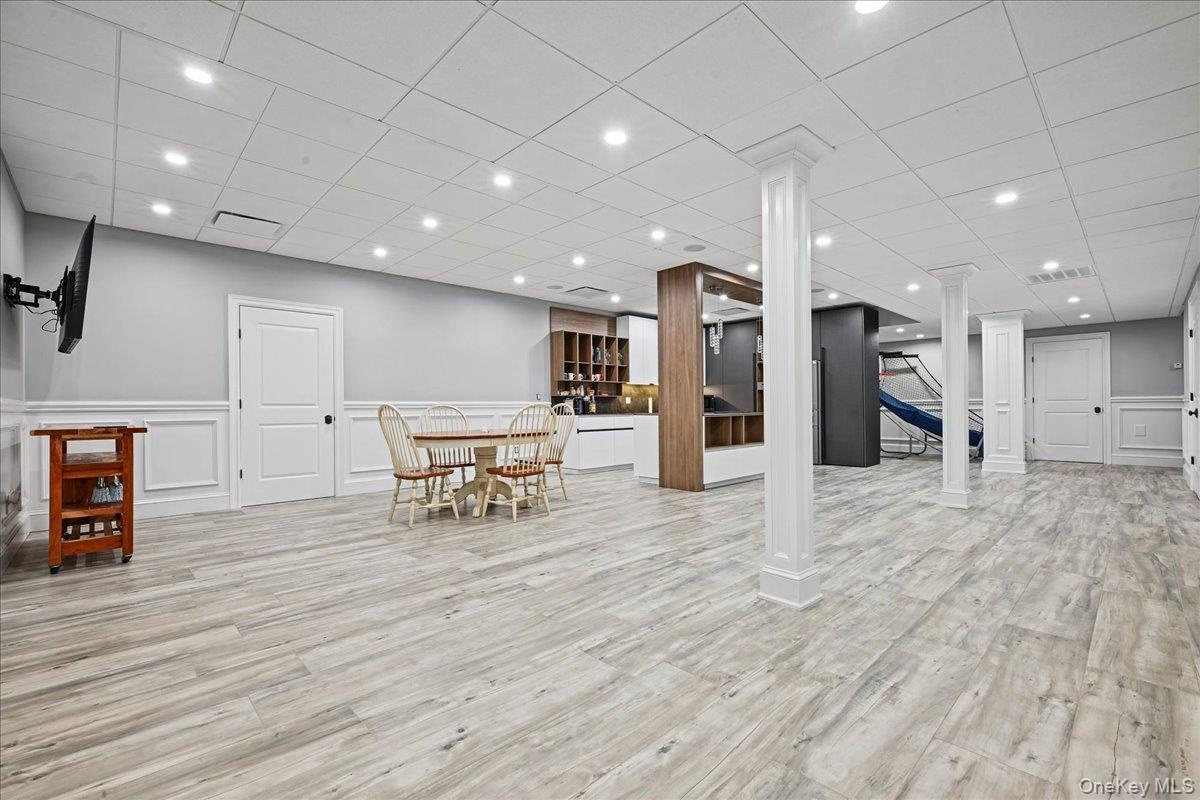 Recessed lighting illuminates the wood-finish flooring, wainscoting, and white trim