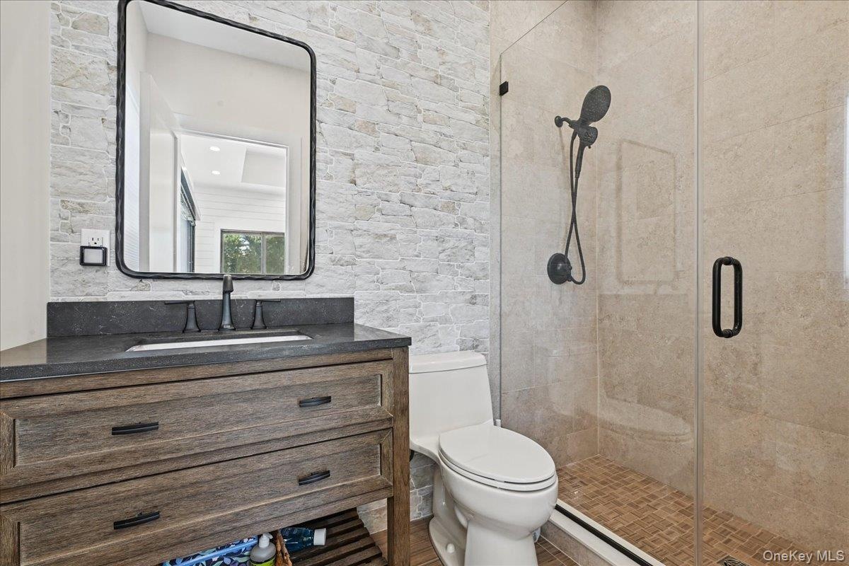Wood-finish vanity with dark countertop and undermount sink - pool house