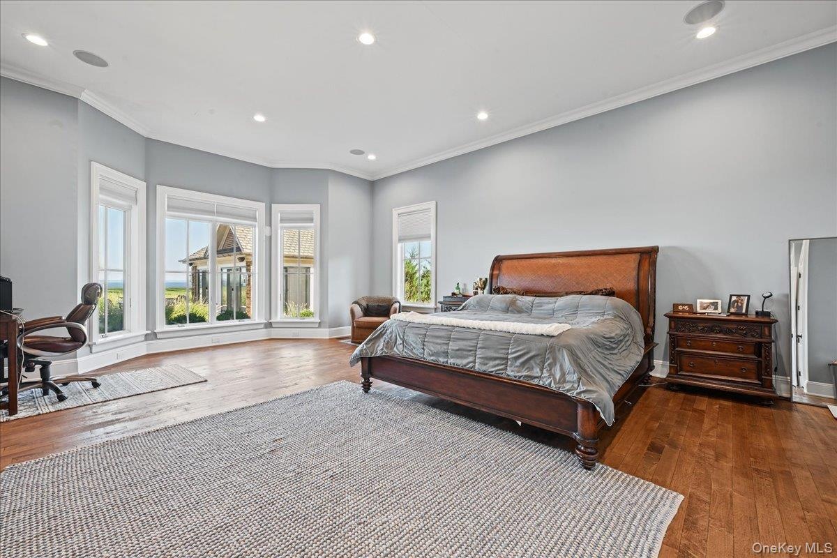 Hardwood flooring, recessed lighting, crown molding, bay window, and light gray wall paint