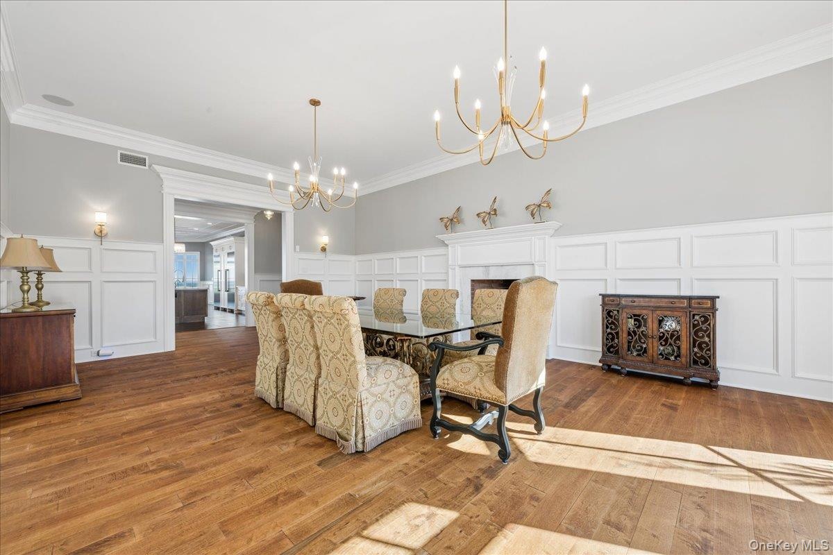 Hardwood flooring, wainscoting, decorative fireplace, crown molding, and wall sconces
