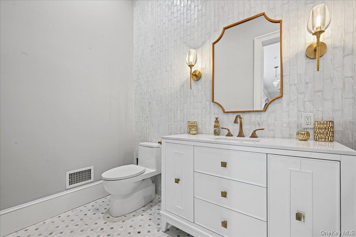 White vanity with gold-tone hardware, white countertop, and gold-tone faucet