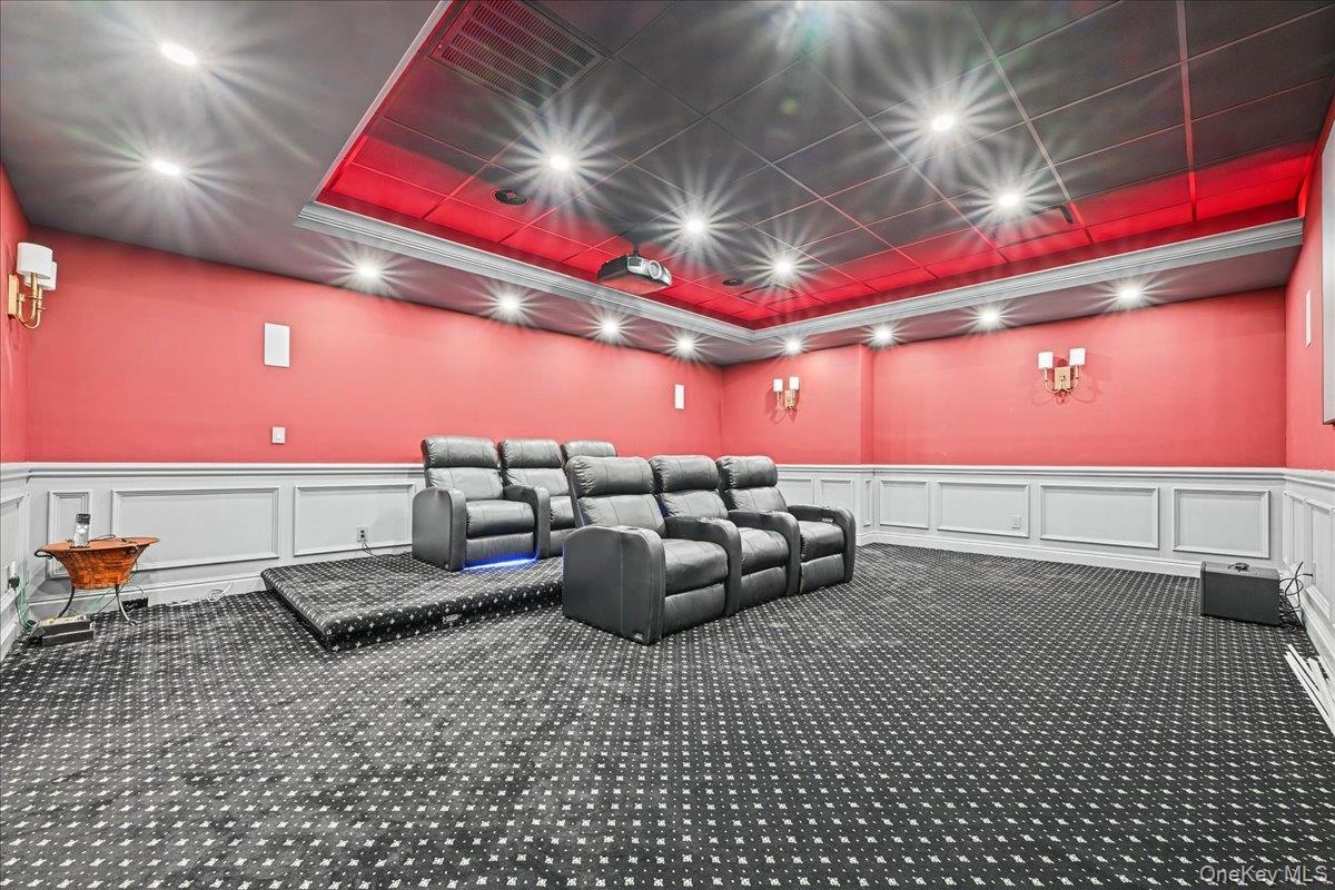 Dedicated media room featuring patterned wall-to-wall carpeting, wainscoting, and recessed lighting