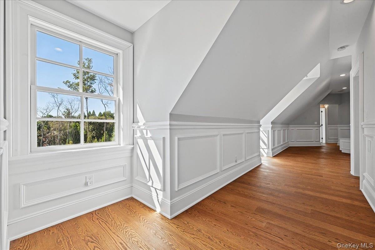 Hardwood flooring, white wall paneling, double-hung window, white trim, recessed lighting