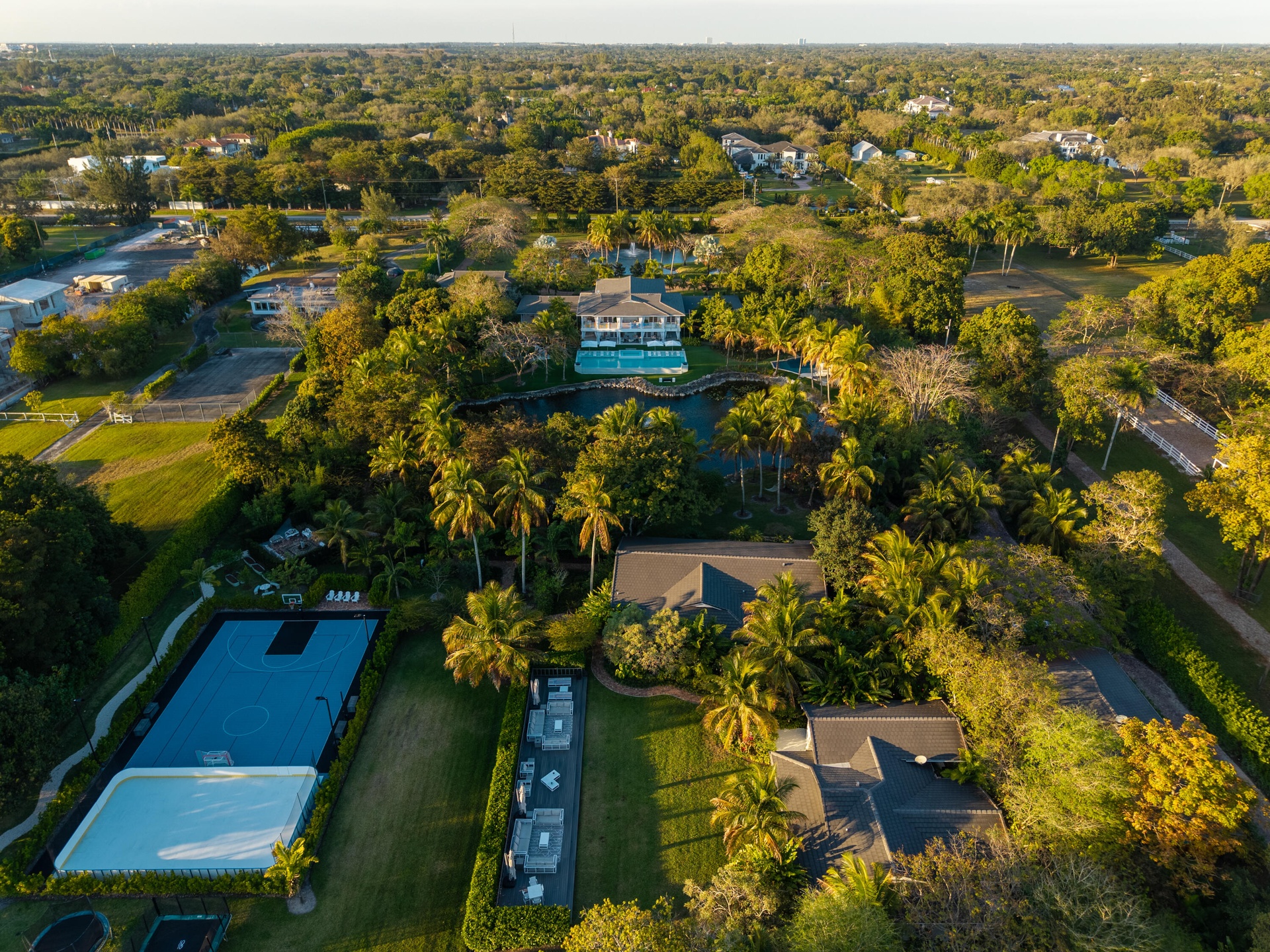 MIDDLE OF PROPERTY AERIAL. BASTBALL COURT AND OUTDOOR ICE SKATE. GUESTHOUSE, CLUBHOUSE, AND SPA/GYM HOUSE