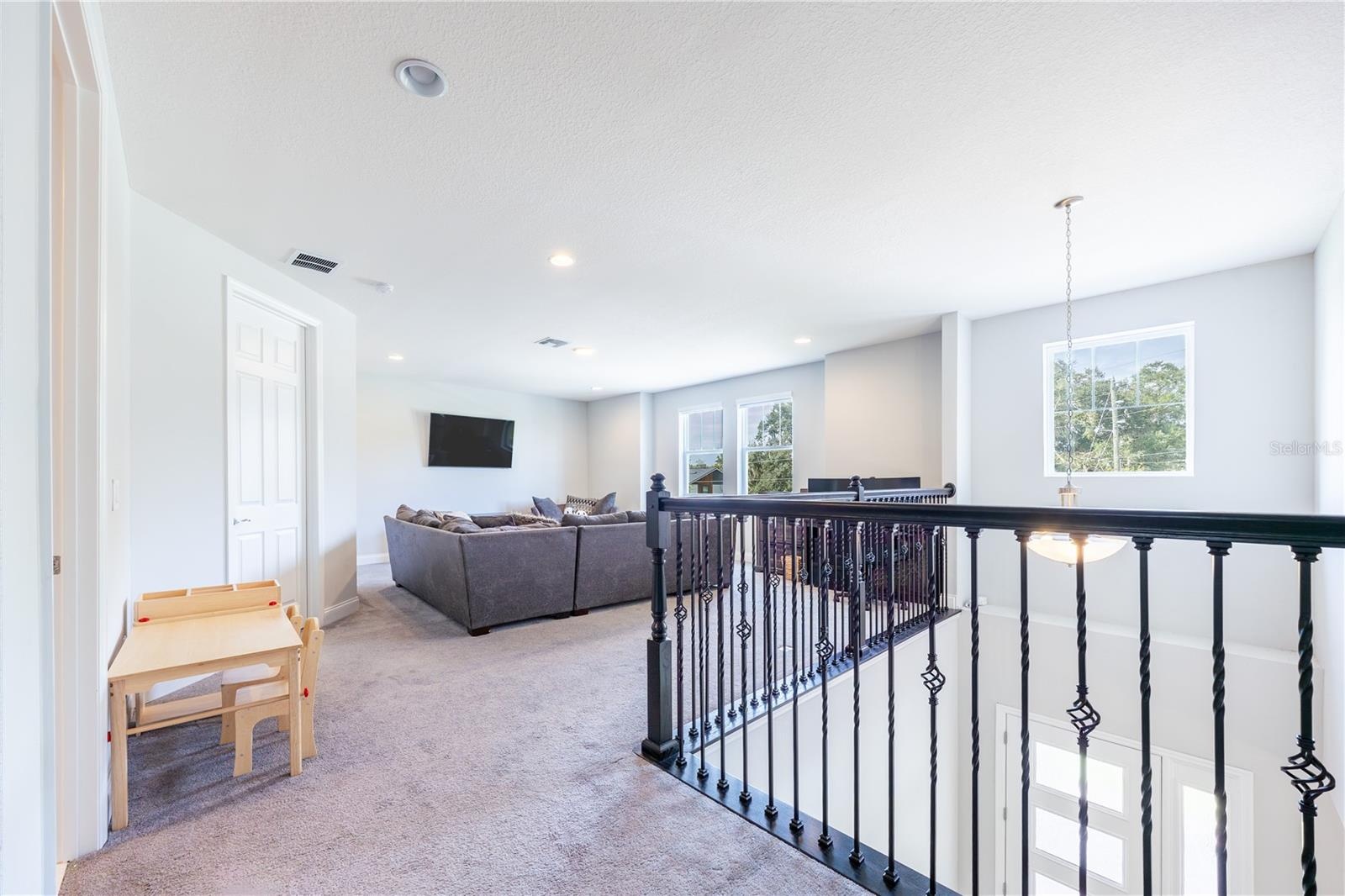 Spacious upstairs loft with a comfortable lounge area and decorative metal railings overlooking the foyer.
