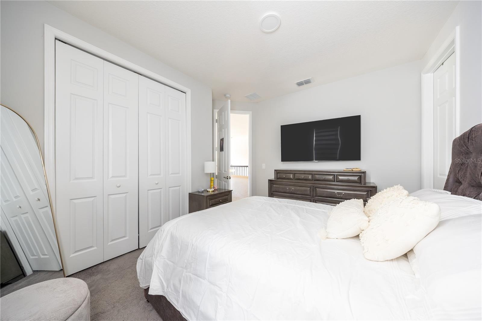 Comfortable bedroom with a spacious closet, soft carpeting, and a refined neutral palette.