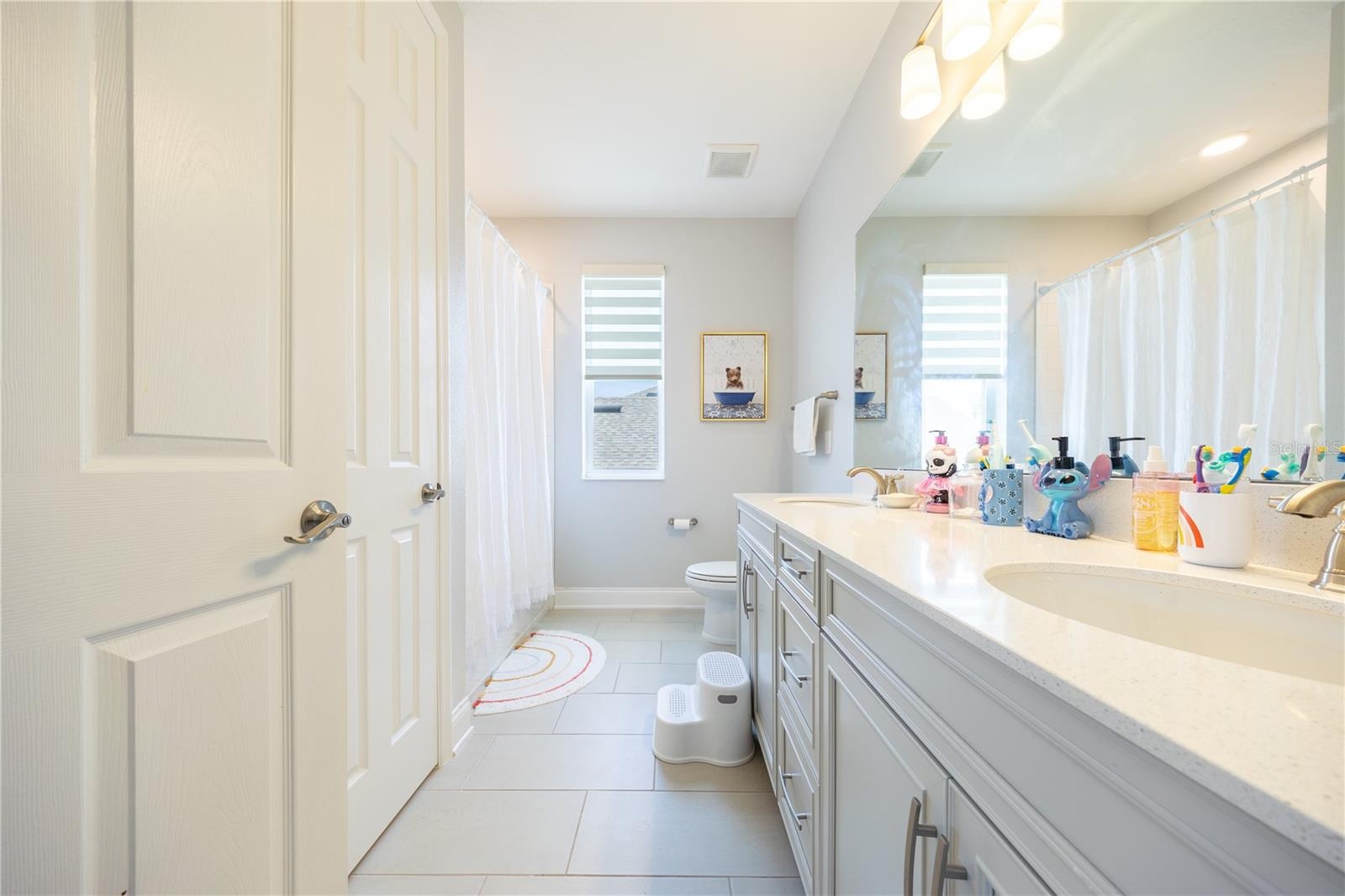 Well-appointed bathroom with a dual-sink vanity, ample storage, and a tub-shower combination.
