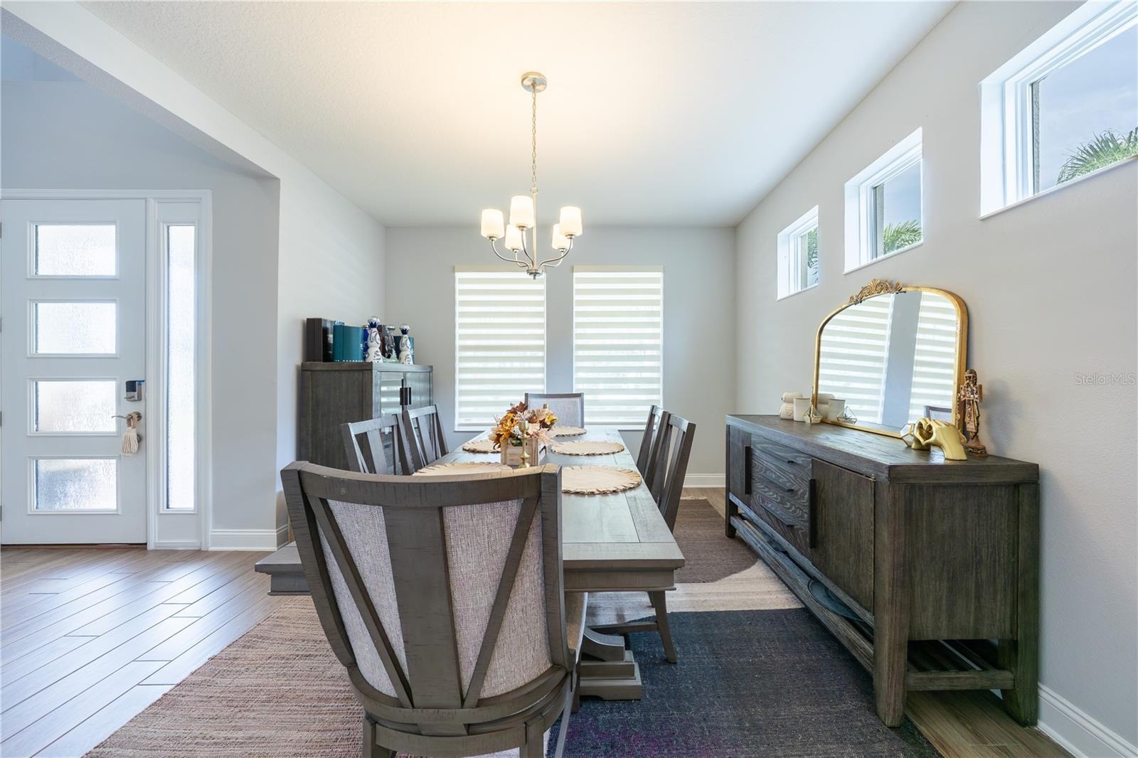 Elegant dining room with high windows and a classic chandelier, just off the foyer.