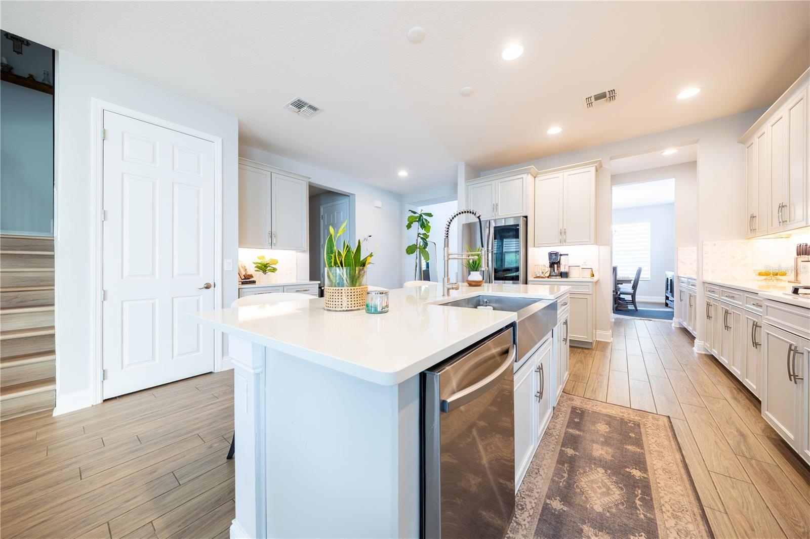 Spacious kitchen island featuring a stainless steel apron-front sink, pull-down faucet, and integrated dishwasher.