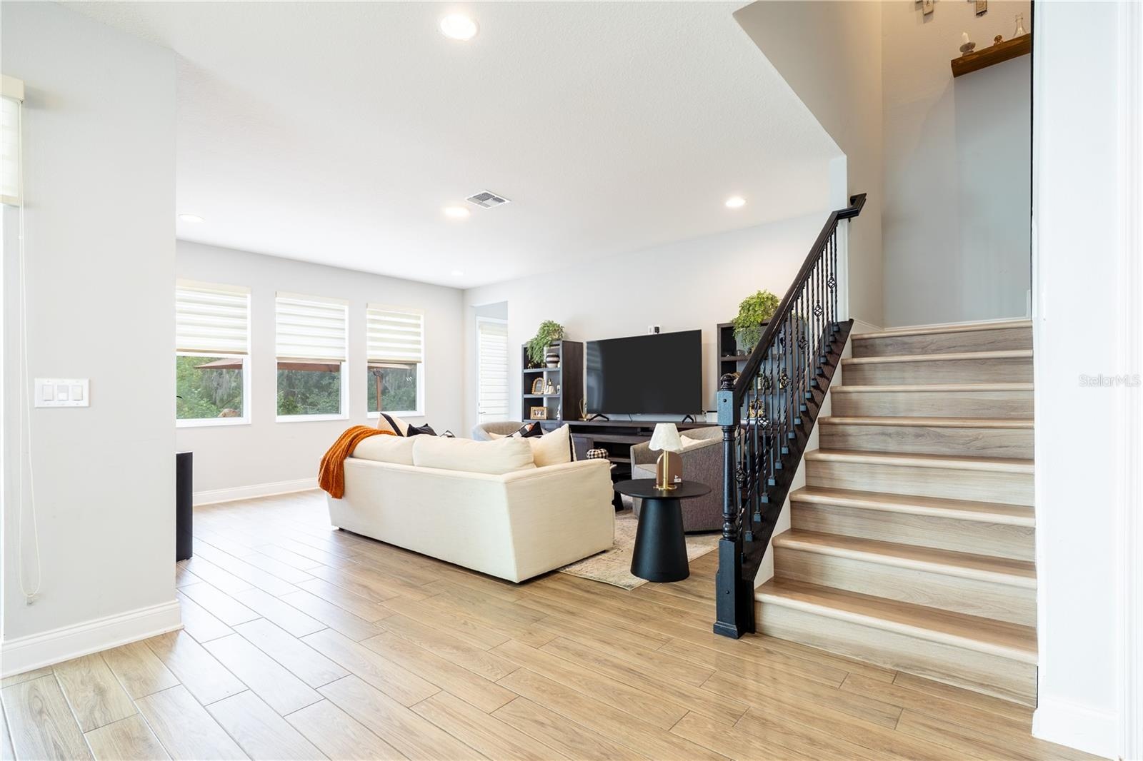 Elegant staircase with decorative metal railings beside an inviting living room with garden views.