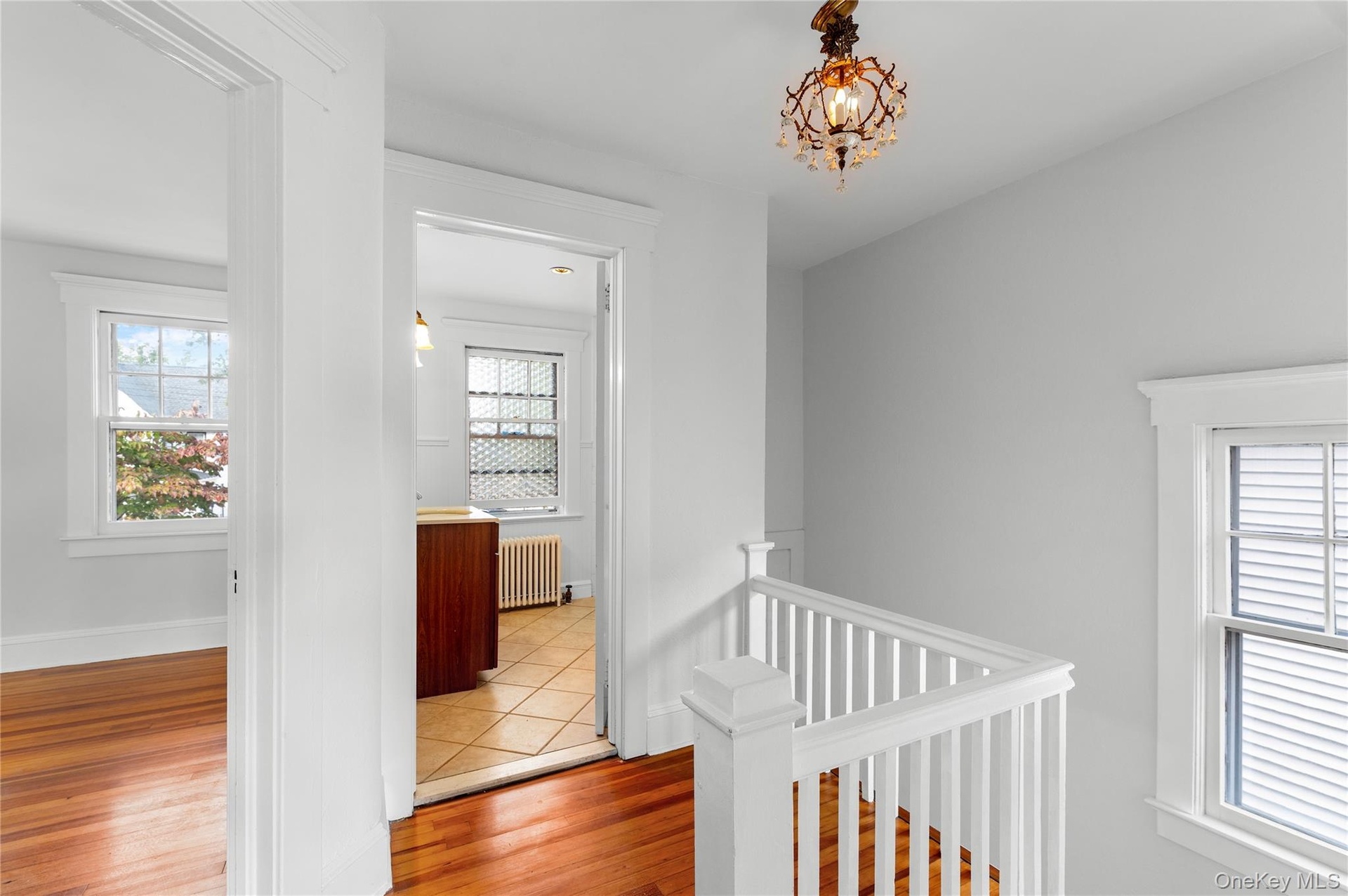 Hallway upstairs, original light fixture, hardwood floors, door to full bath