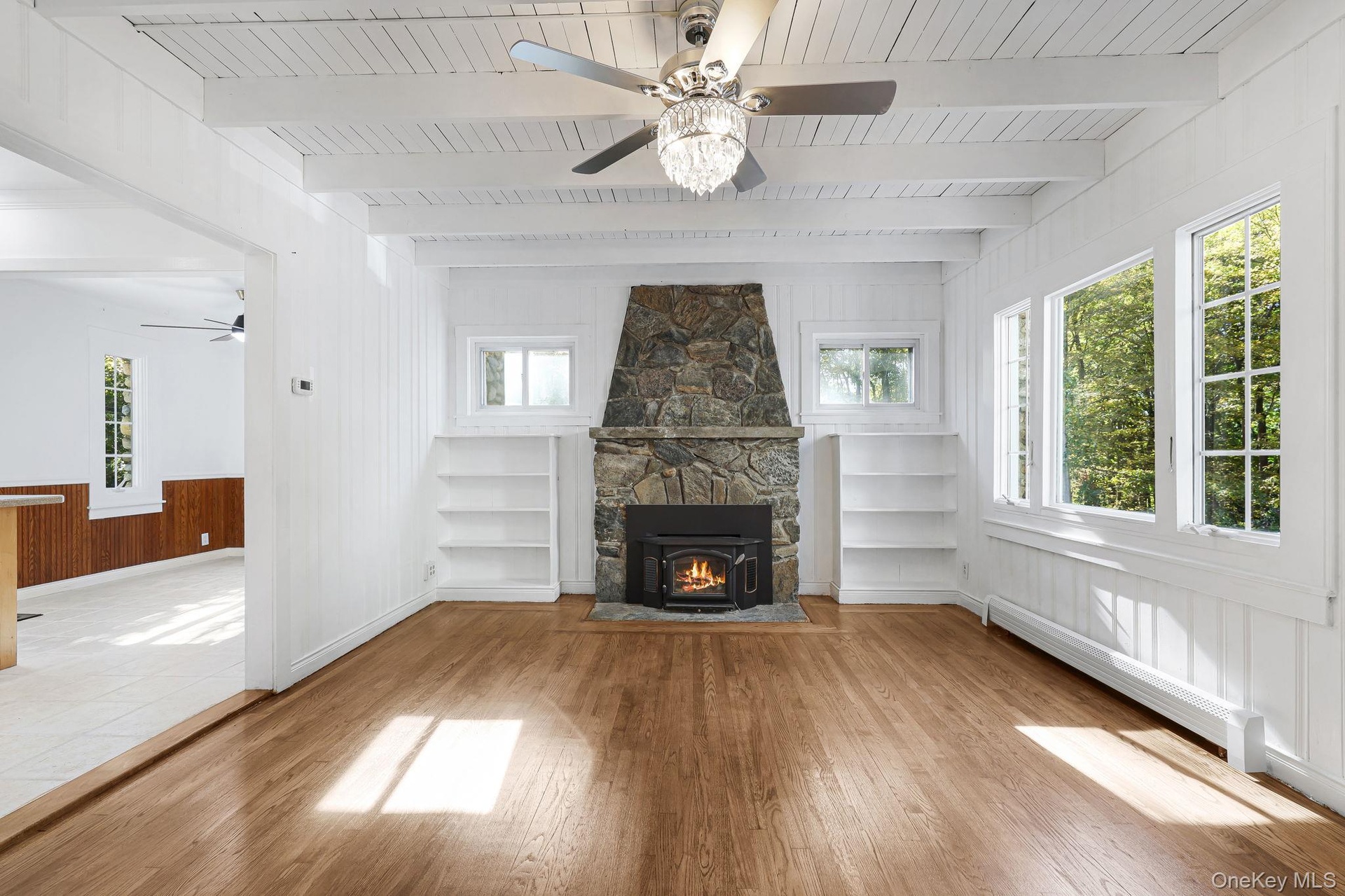 Living room with built in Book Shelves, Floor to Ceiling Stone Fire Place, and Plenty of Natural Light