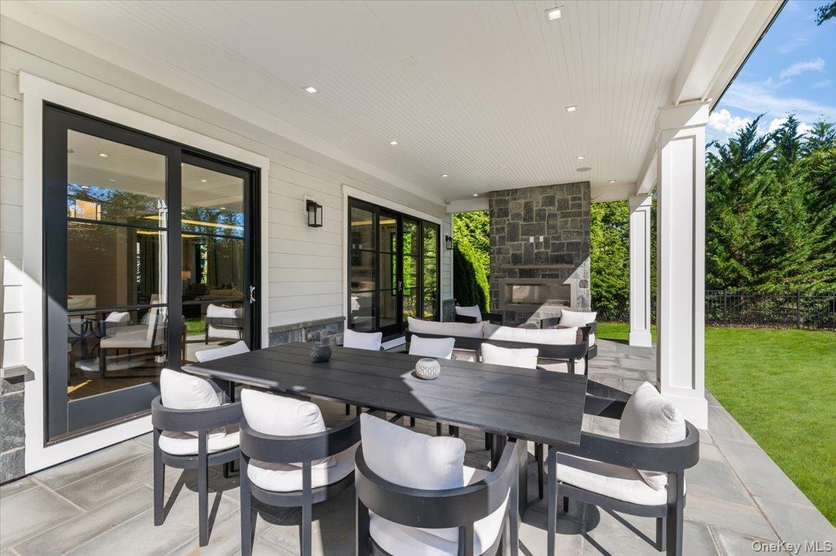 Covered patio with stone flooring, recessed lighting, and a stone-clad outdoor fireplace