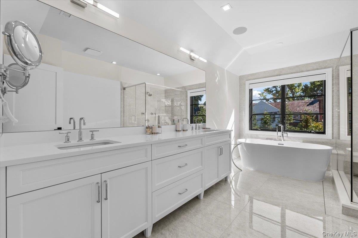 Dual vanity with white cabinetry, polished chrome fixtures, and a large integrated mirror