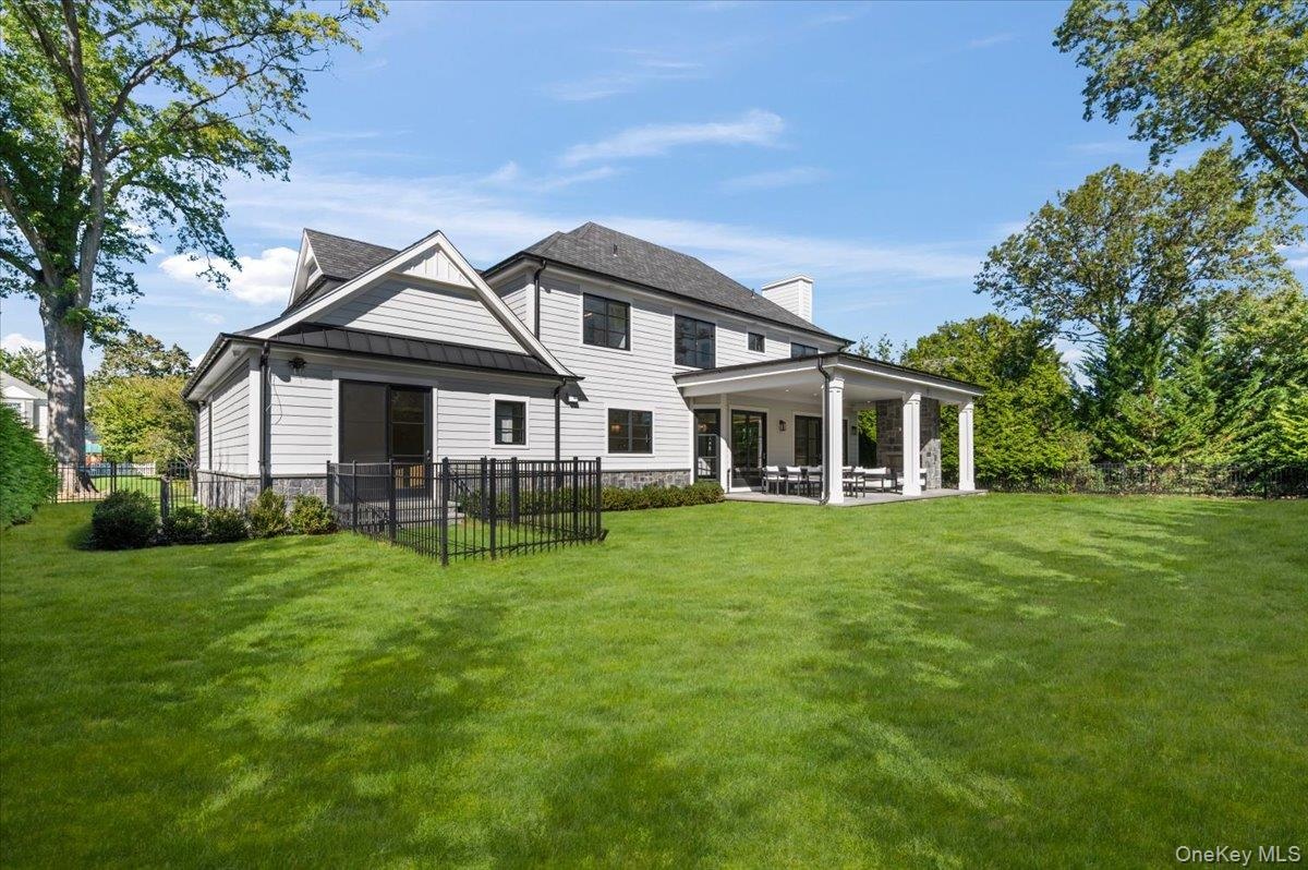 Expansive grass lawn with a covered patio featuring stone columns and Dog Pen