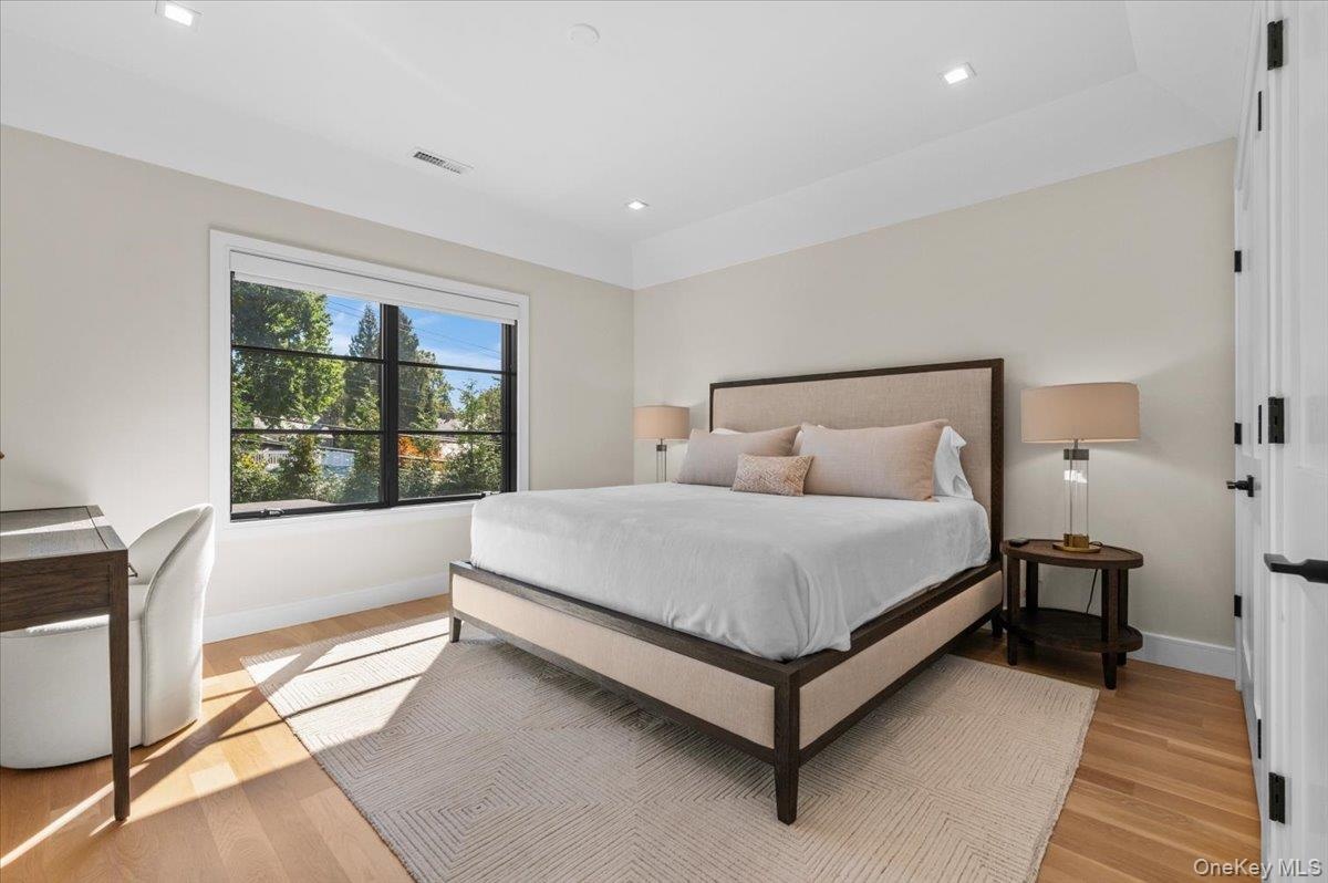 Recessed lighting, wood-finish flooring, and a large window with black framing