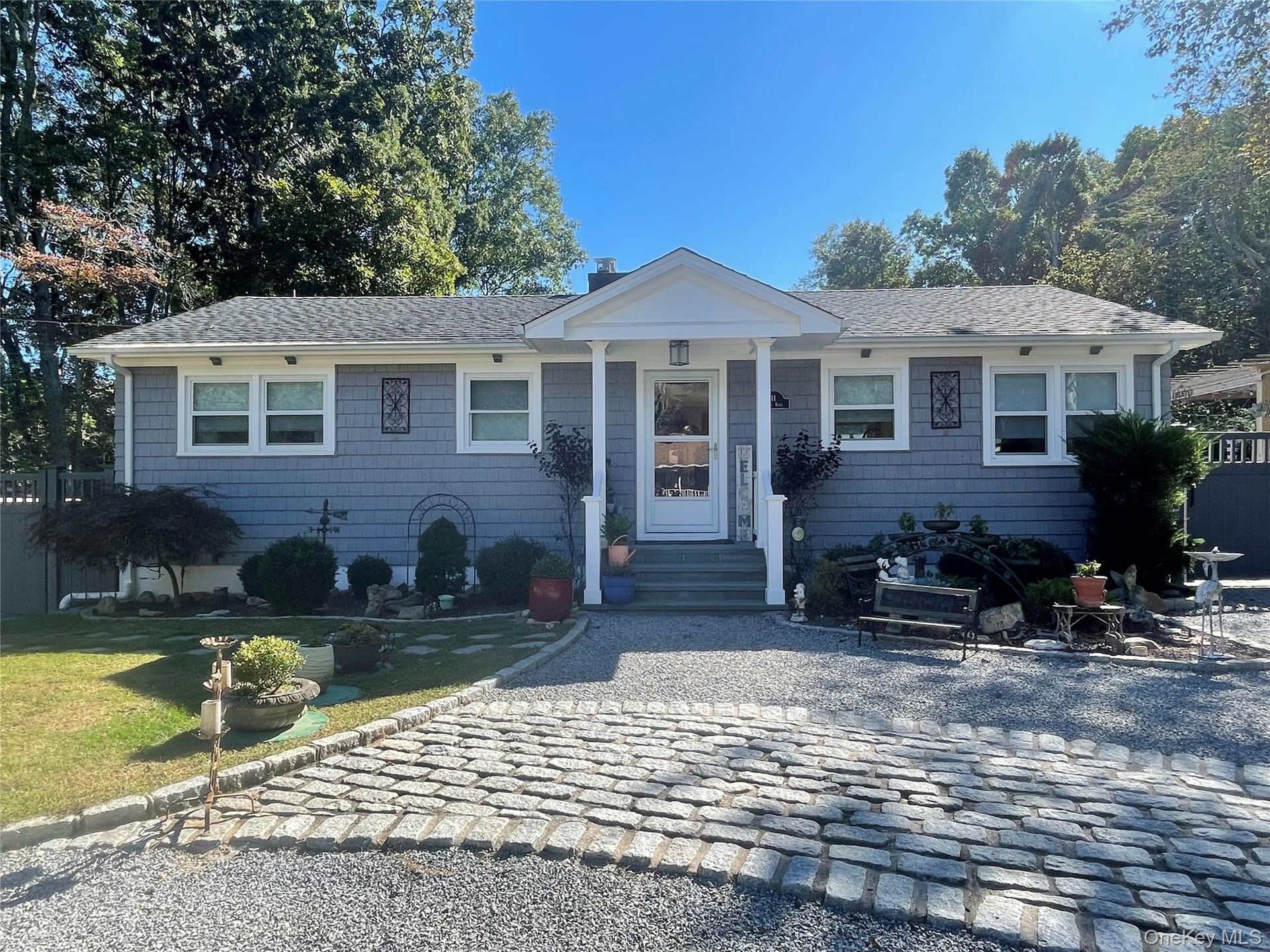 Very Pretty Siding exterior with white trim, covered front entry porch, steps with handrails, and a paver stone driveway