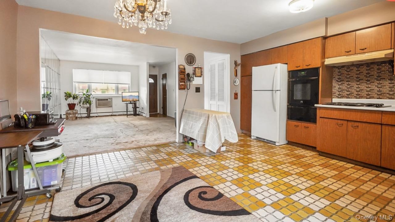 Kitchen with wood cabinetry, built-in double oven, and patterned floor tile