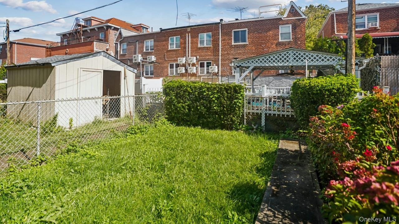 Expansive yard space featuring a storage shed, chain-link fencing, and mature plantings