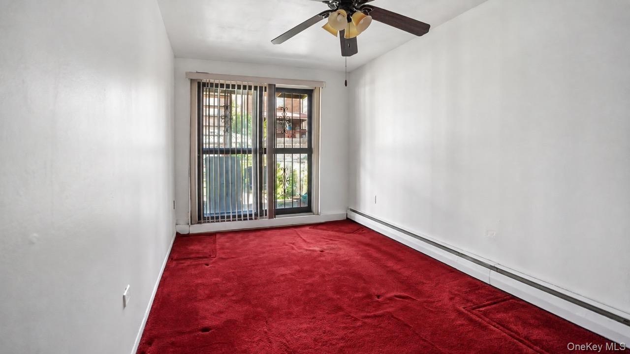 Sliding glass door with vertical blinds, ceiling fan with integrated lighting, and red carpeting