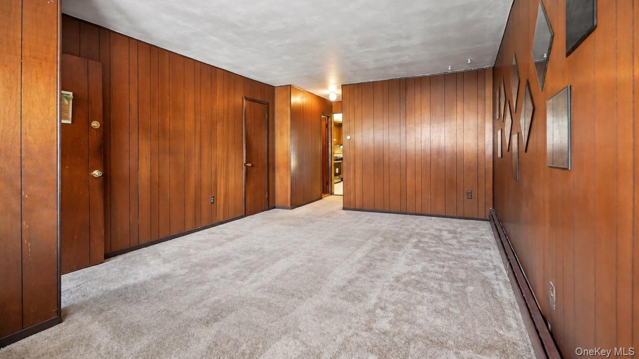 Wall paneling with a rich wood tone, light gray carpeting, and white ceiling finish