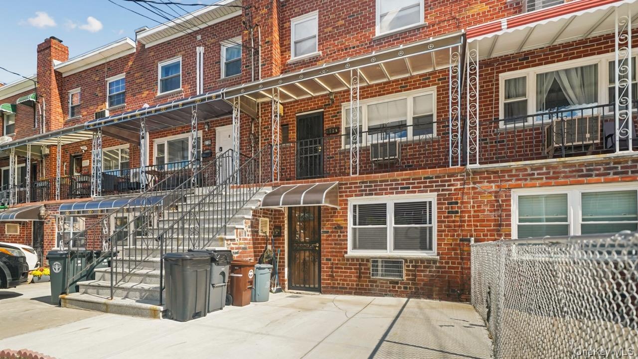 Brick exterior with multiple windows, a covered front entrance, and a chain-link fence