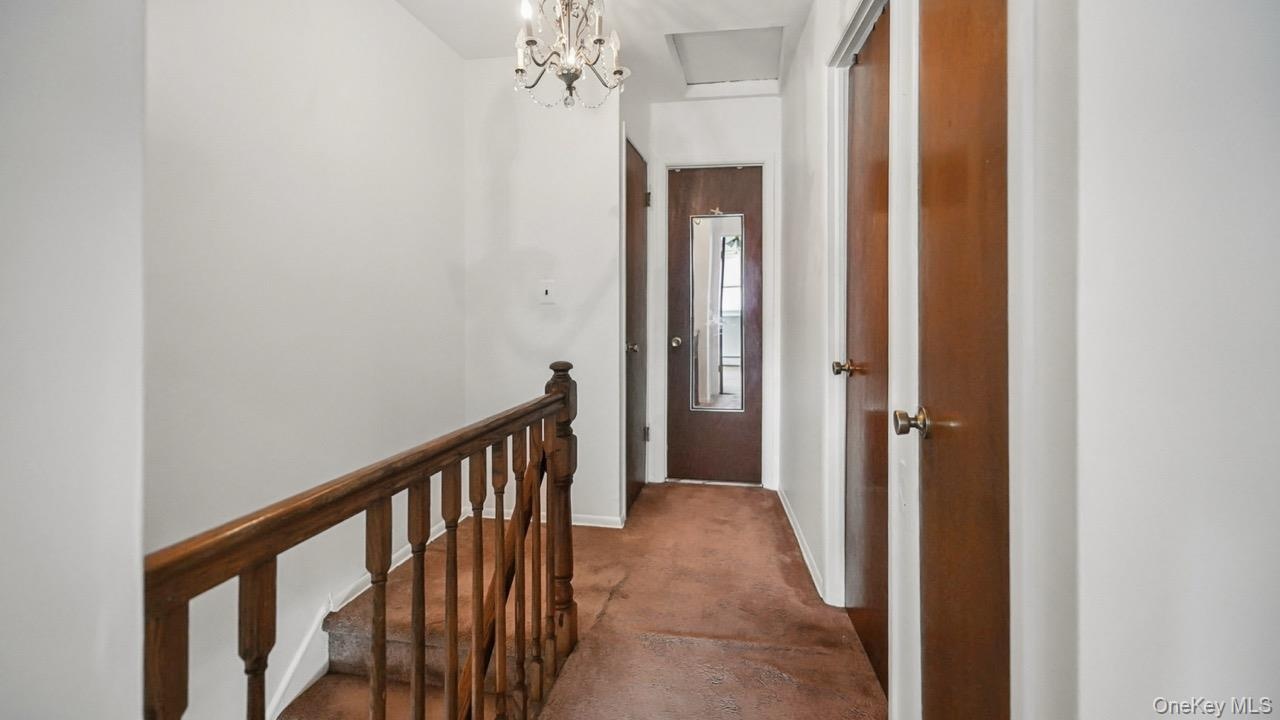 Carpeted hallway with wood doors and a chandelier light fixture