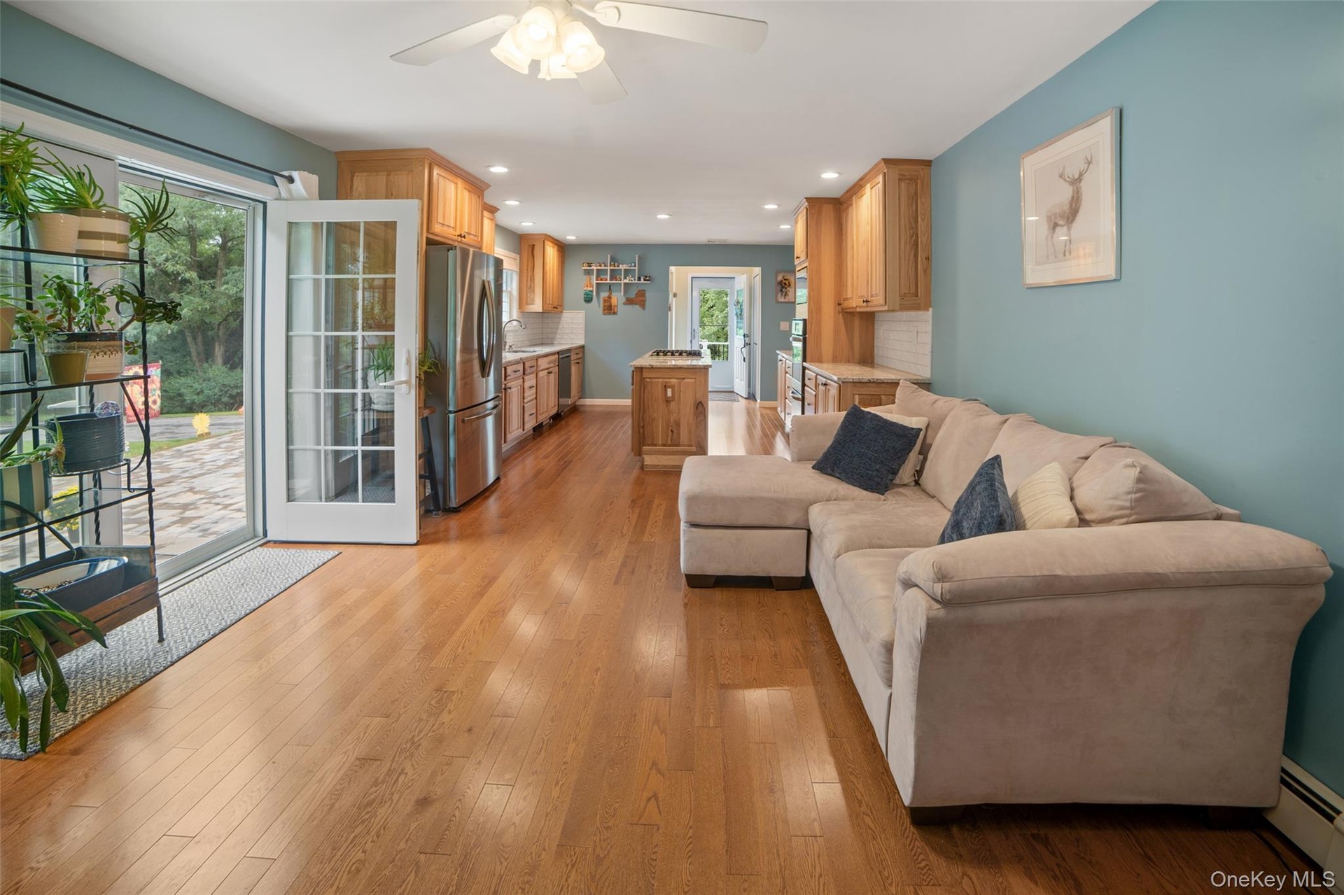 Hardwood flooring throughout, kitchen with stainless steel appliances, light wood cabinetry, and a large island