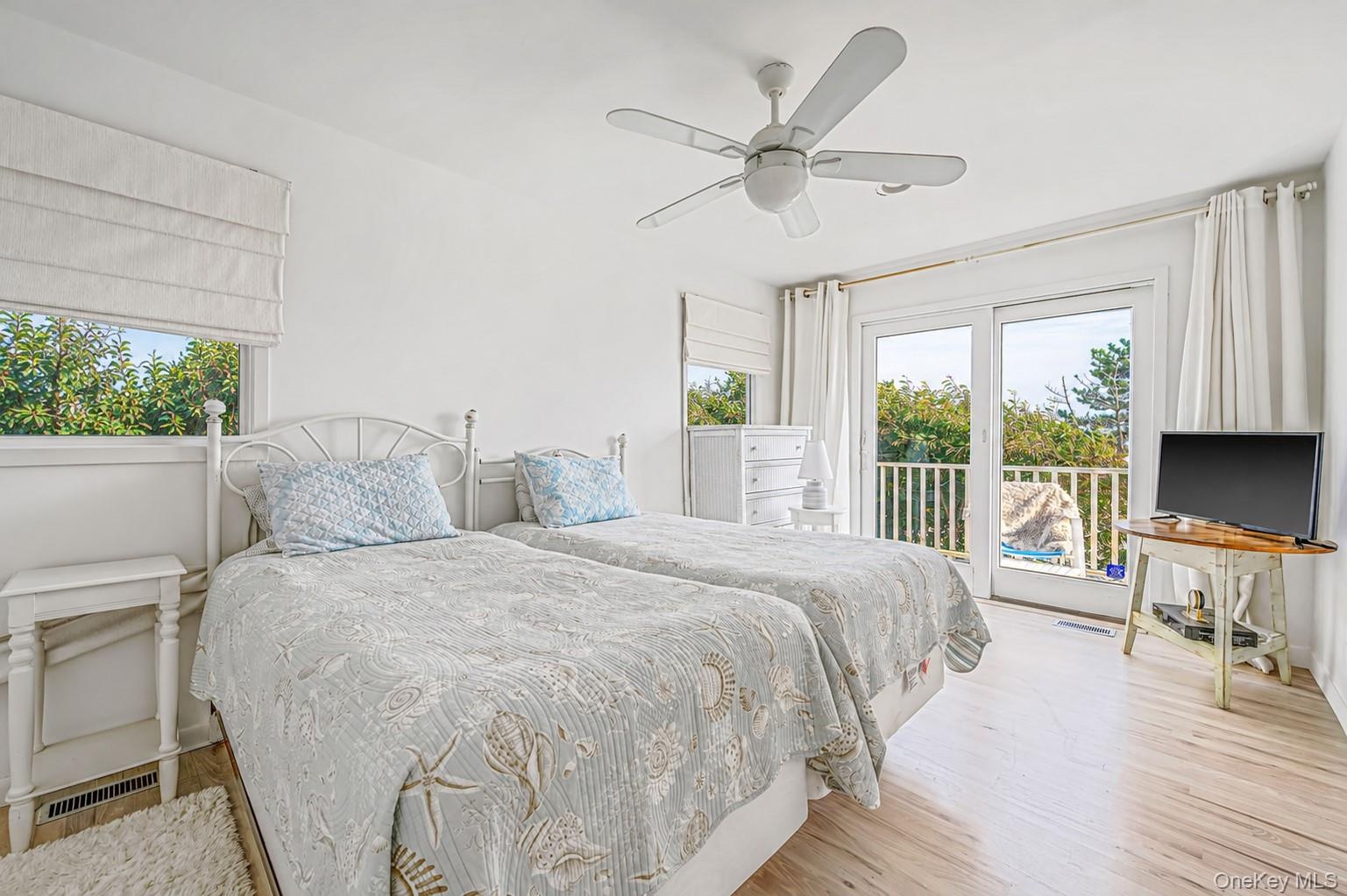 Dual window treatments, ceiling fan, sliding glass door to exterior, and wood-finish flooring