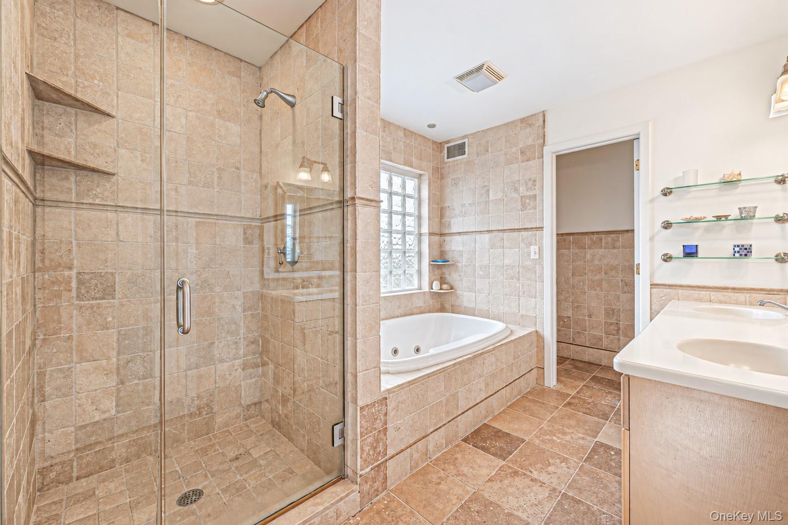 Glass-enclosed shower with tile surround and built-in shelving