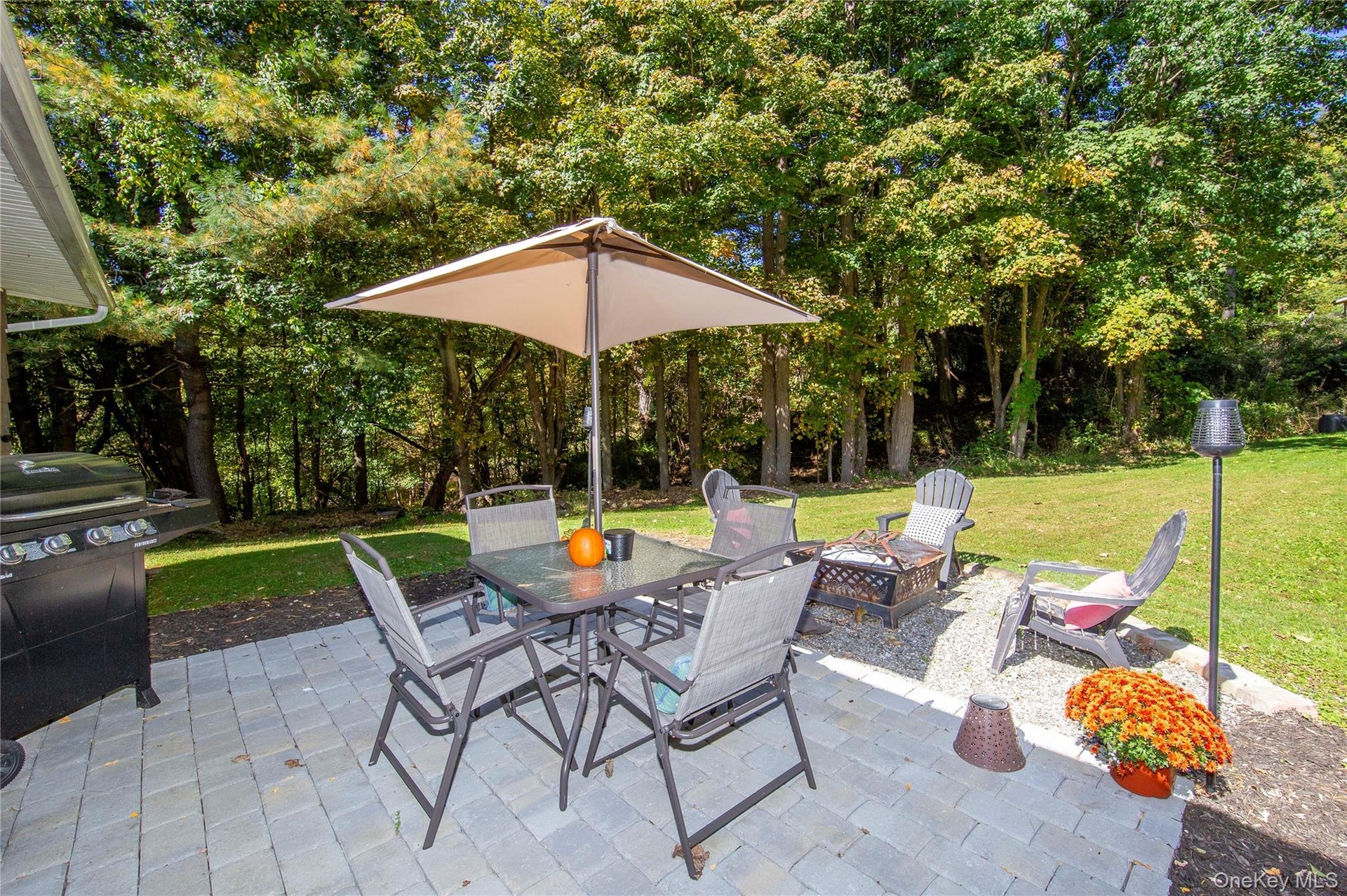 Complete with a BBQ grill, dining set, chairs, and a firepit.