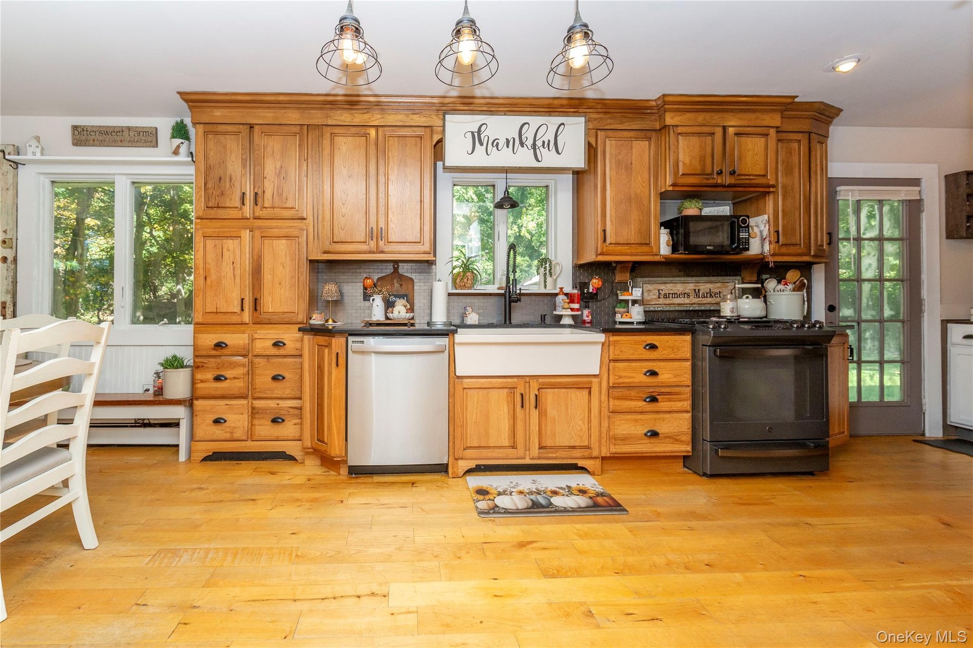 Warm honey-toned cabinetry is complemented by black granite countertops and updated stainless steel and black appliances.