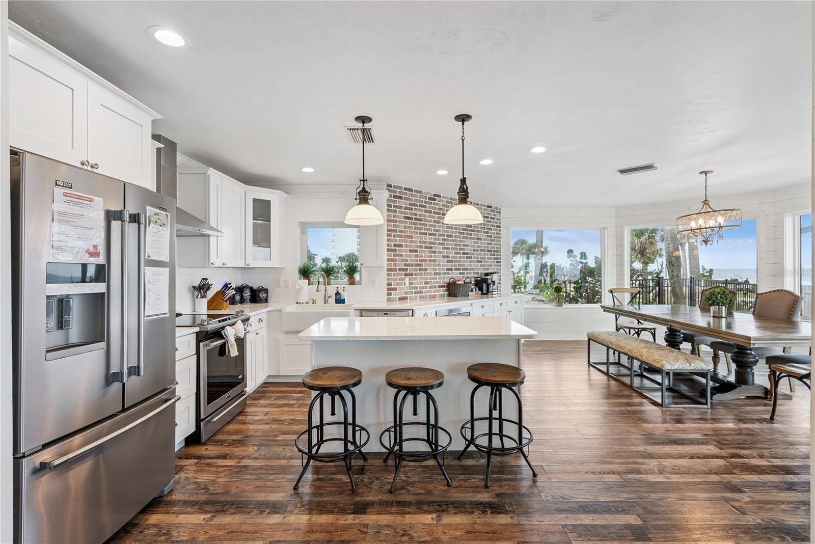 Spacious eat-in kitchen with stainless steel appliances, quartz countertops, breakfast bar seating, and beautiful ocean views—an inviting setting for 